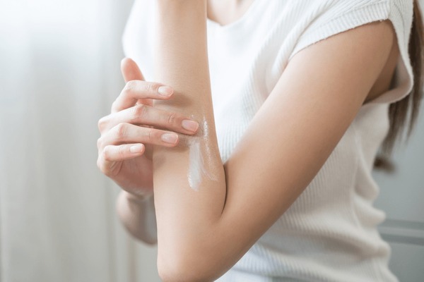 person applying body lotion to arms natural light